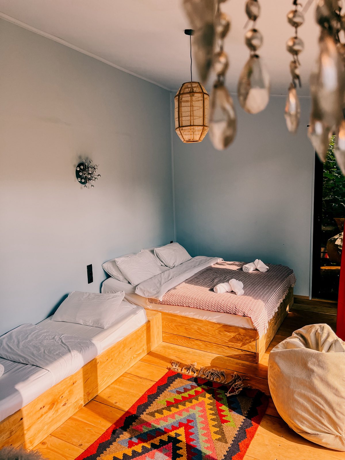 A room with a king-size bed, an extra single bed, a colourful kilim rug and a beanbag.